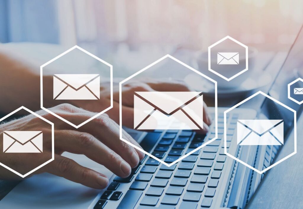 Image shows a person typing on a laptop with symbols for emails scattered across the image to signify newsletters.